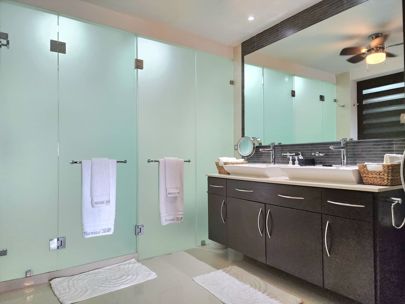 Bathroom with frosted glass partitions and a ceiling fan overhead