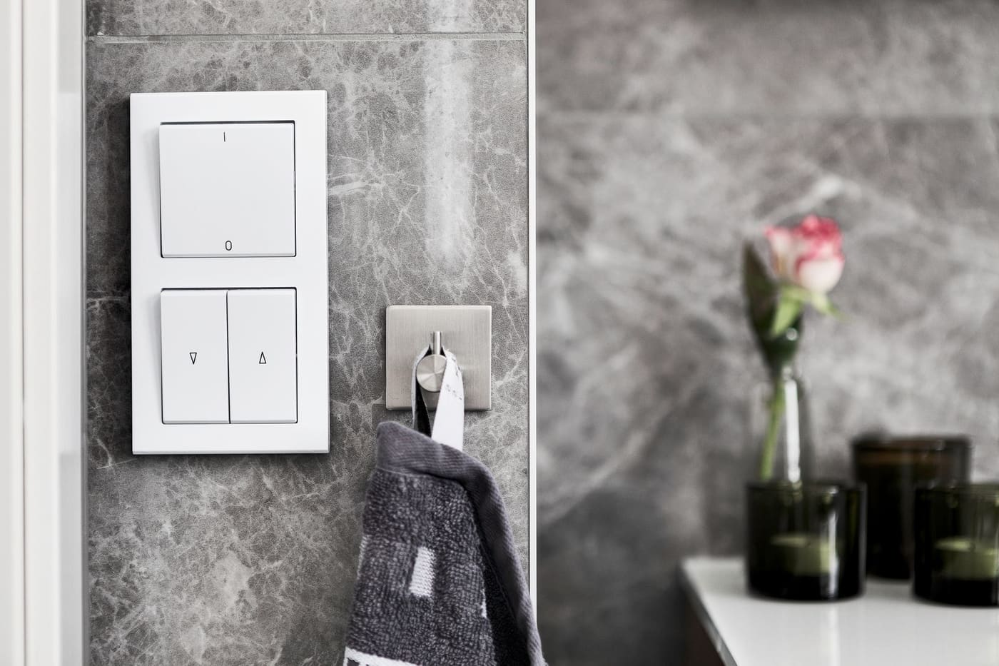 Grey towel hanging from a hook on a marble wall
