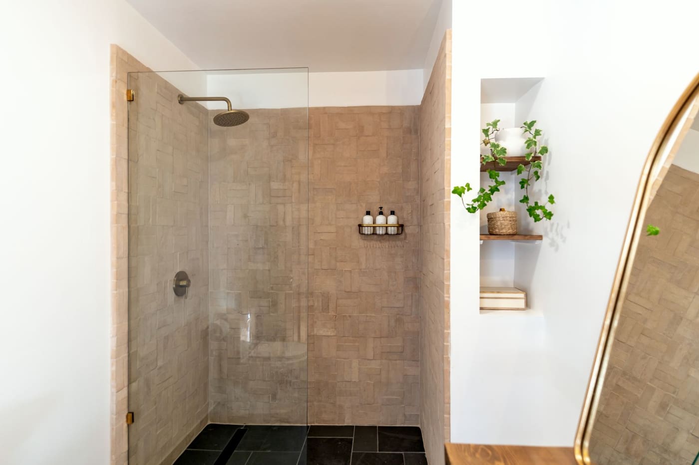 Walk-in shower with a small wall-mounted basket holding three bottles