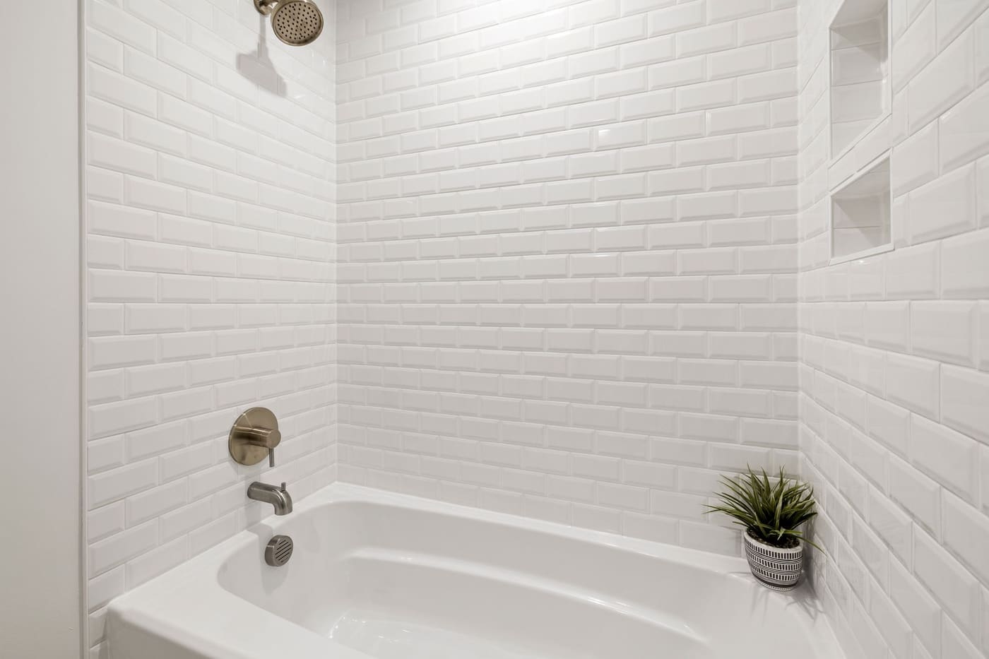 White subway-tile tub alcove with two small recessed niches