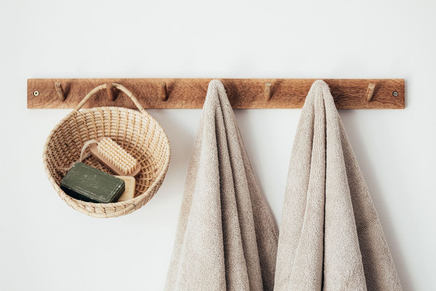 Wooden hook rail with two towels and a small wicker basket