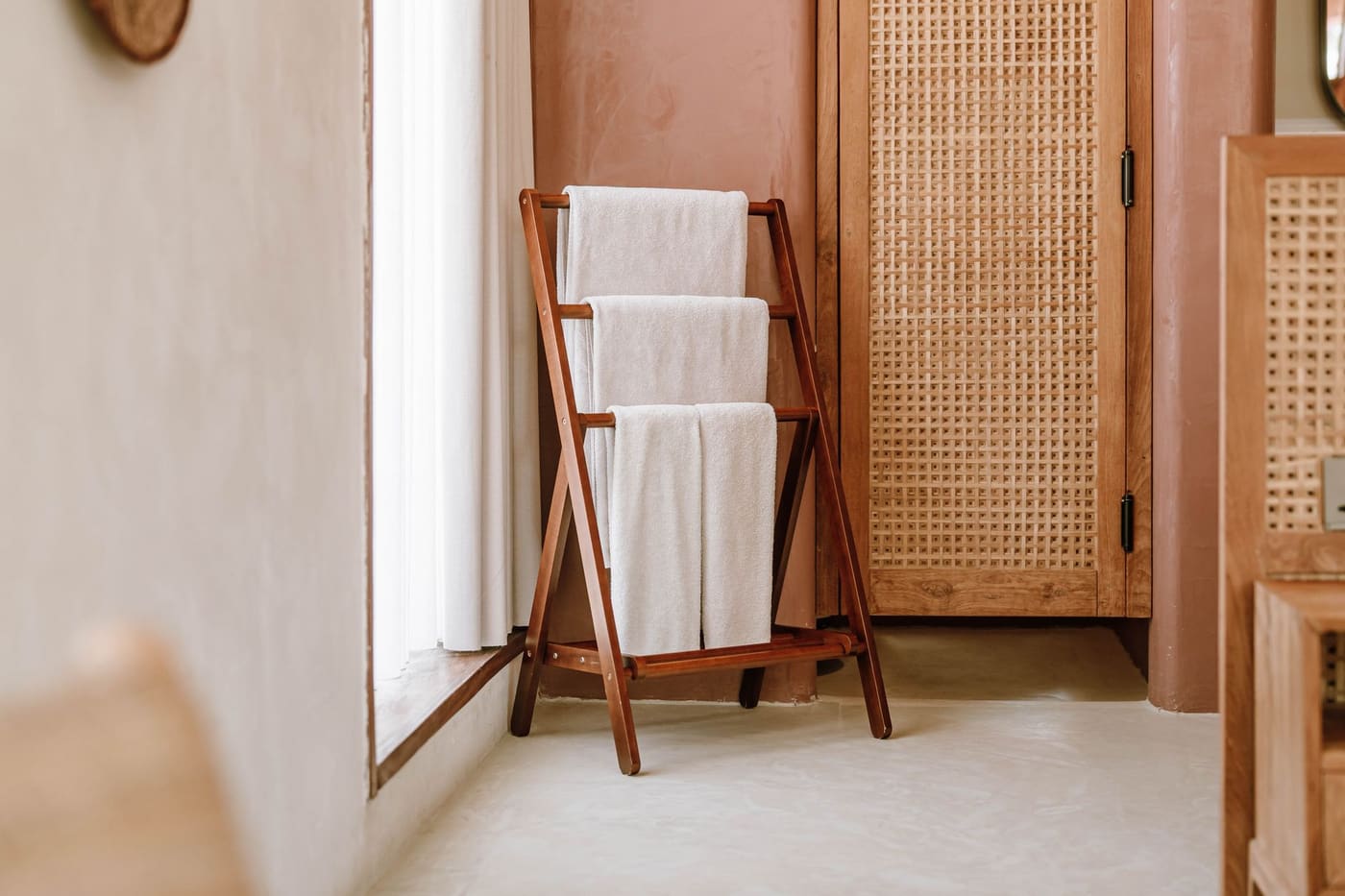Wooden towel rack with folded white towels in a bathroom