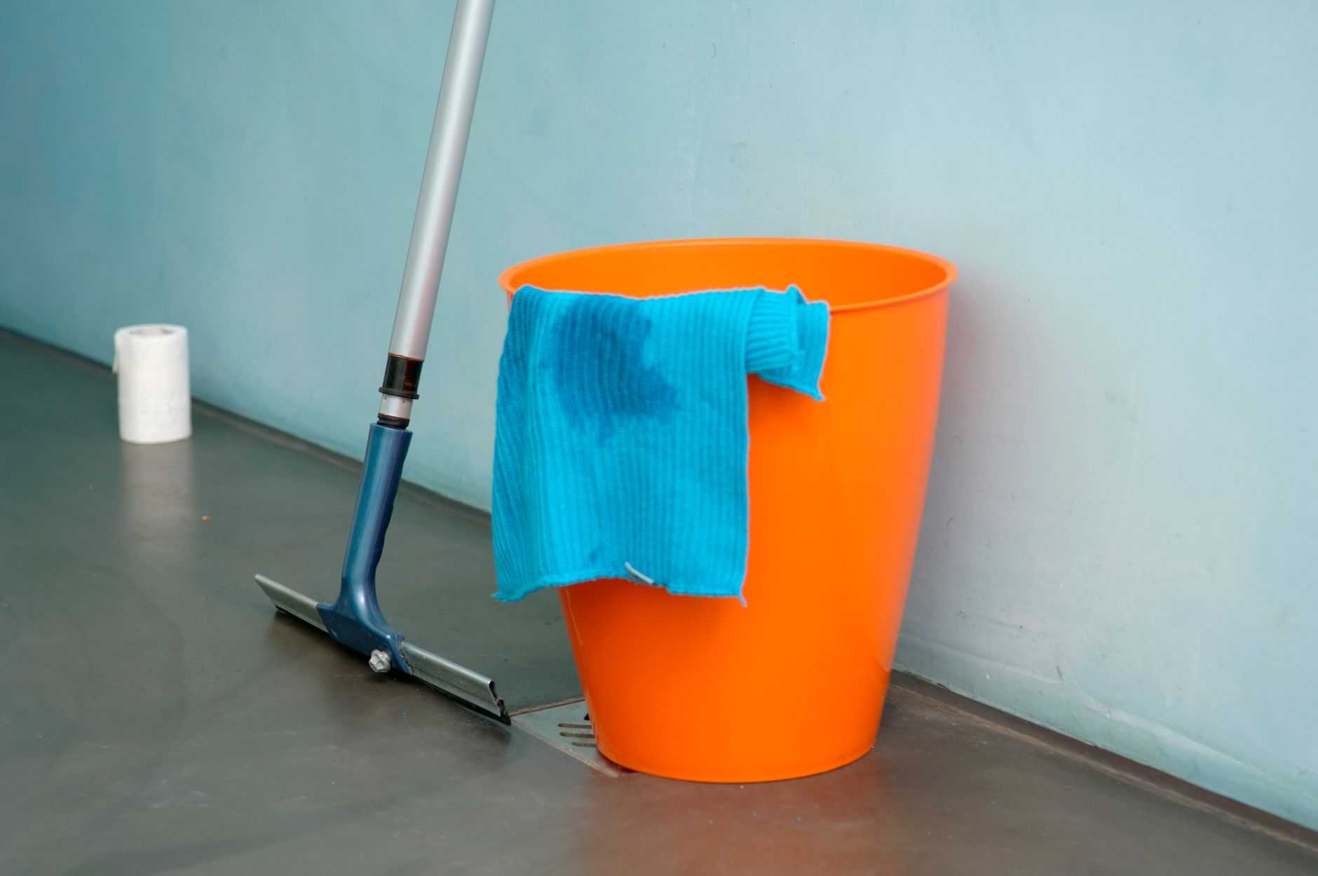 Cleaning supplies including an orange bucket and mop